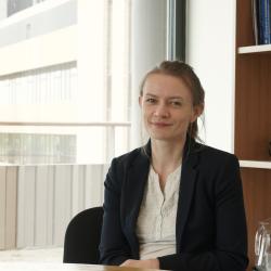 Dr Ewa Marek smiles at the camera in an office with a big window behind