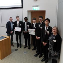 A group of students smile at the camera while holding a prize check