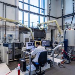 A man sits at a computer in a large laboratory