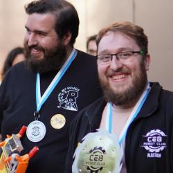 Two men hold a winner's trophy and a small robot